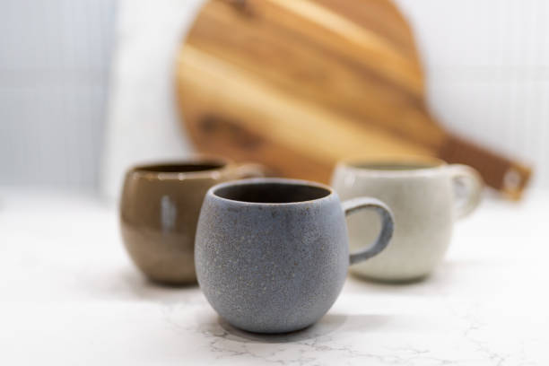 istock Set of three rustic ceramic mugs on kitchen counter. Stack of handmade stoneware mugs. 1452762228