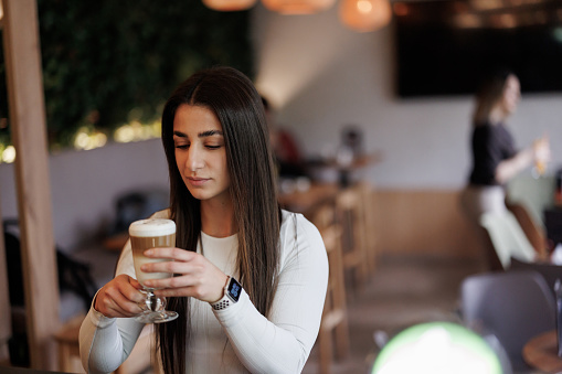 Beautiful young woman enjoying latte in favorite coffee shop