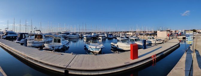 A panoramic view of an old narrow wooden harbor with boats on each side