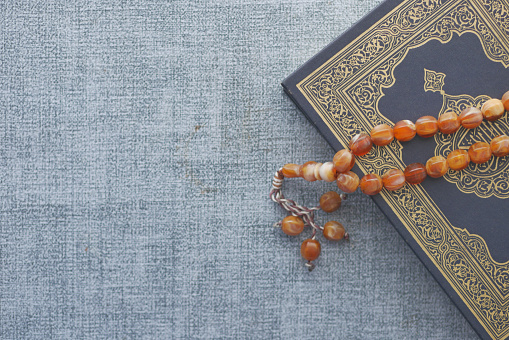 Holy book Quran and rosary on table, close up