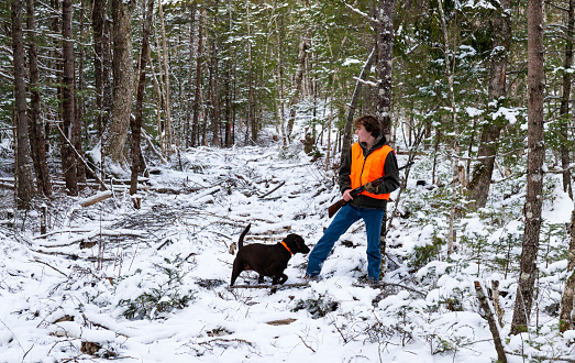 A teenager grouse hunting with his Labrador Retriever on a frosty Autumn day.