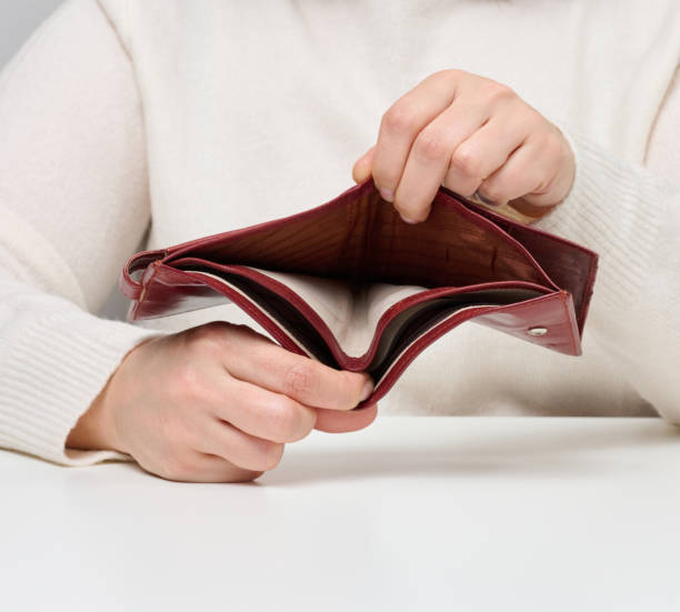 istock Two female hands hold an empty brown leather wallet, poverty 1452771585