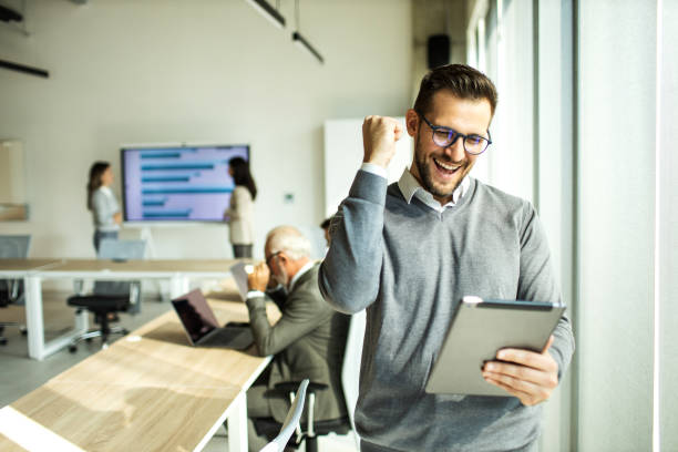 Confident young man businessman working inside modern office on a digital tablet