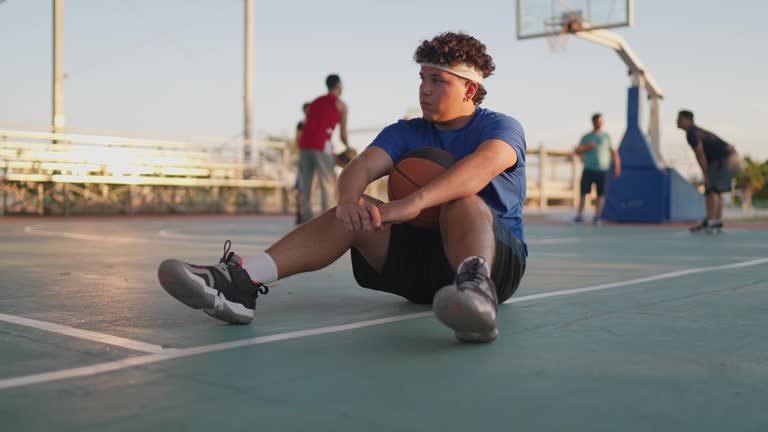 Basketball player sitting on the sports court