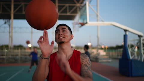 Young man spinning a basketball ball at a field