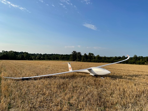 Sailplane ‎⁨near Neuvy-Saint-Sépulchre⁩, ⁨France⁩ - 8/10/21: A color photograph of a sailplane the has landed in a farmer's field, during the WGC, Montlucon, France