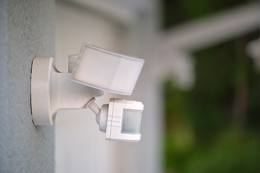 Sensor de movimiento con detector de luz montado en la pared exterior de la casa privada como parte del sistema de seguridad photo