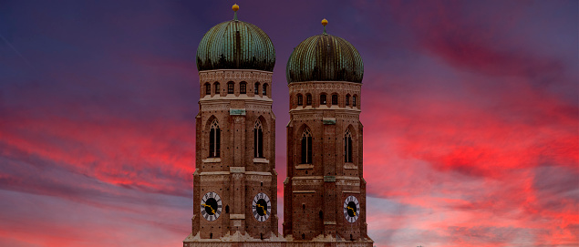 The two towers of the Frauenkirche in the old town of Munich against dramatic, colorful evening sky with light to medium cloud cover