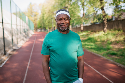 Portrait of healthy senior man standing on running track at exercise court
