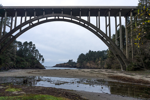 Concrete suspension bridge with the pacific coast in the background.