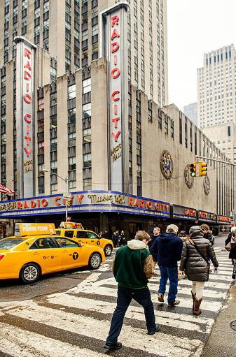 New York City, USA - February 18, 2014: Radio City Music Hall located at 1260 6th Avenue (Avenue of the Americas) in New York City, USA. Yellow taxis and cars passing by the street