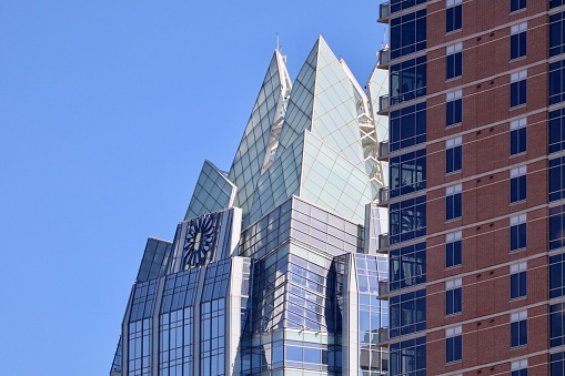 Frost Bank Tower, pictured close up next to a brick residential building, located in the downtown area of Austin, Texas.