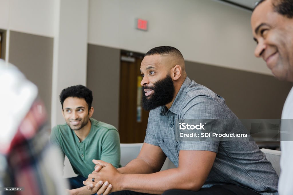 Diverse smile during support group meeting Three diverse men smile during group therapy. Group Therapy Stock Photo