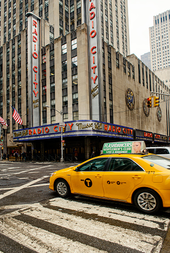 New York City, USA - February 18, 2014: Radio City Music Hall located at 1260 6th Avenue (Avenue of the Americas) in New York City, USA. Yellow taxis and cars passing by the street