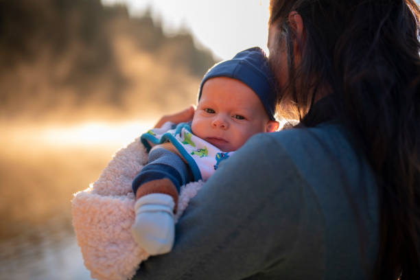 Newborn baby boy on camping vacation with his mother at sunrise.