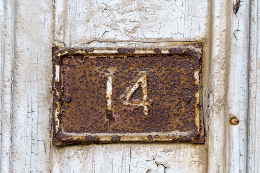 Old sign with the house number 14 on the background of the wall. High quality photo