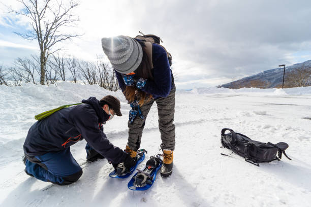 istock Mountain guide helping to put snow shoes on student 1452794605