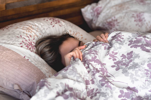 Young girl hiding under bed covers