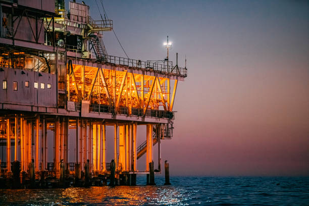 cores do pôr do sol atrás de uma plataforma de perfuração de petróleo offshore em huntington beach - oil rig sea oil well oil drill - fotografias e filmes do acervo