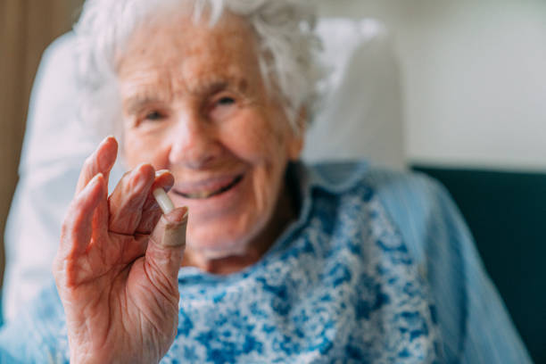Portrait of a 101-Year-Old Woman Holding a Prescription Pill or Vitamin Supplement, and Looking at the Camera Smiling with Copy Space stock photo