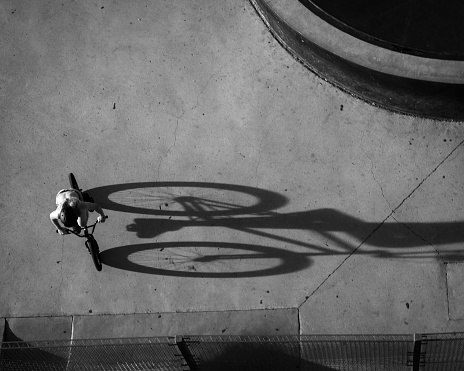 A drone grayscale shot of TX biker at the skate park casting a long shadow