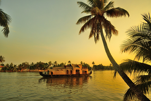 A houseboat sailing in Kerala backwaters during sunset.