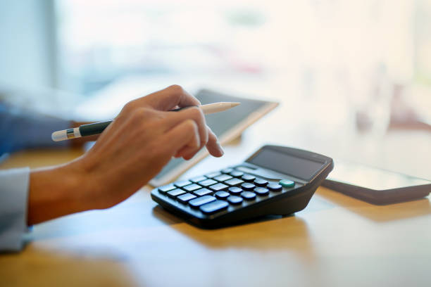 Cropped shot of Asian woman sitting at table doing financial plan and budget with calculator and tablet. stock photo