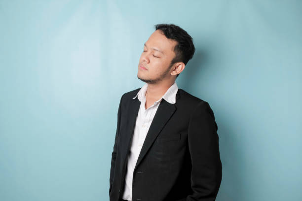 istock Cool businessman wearing black suit standing on blue background 1452816565