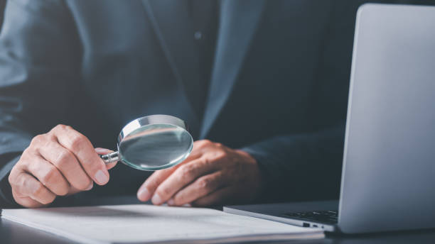 istock Businessman holding a magnifying glass,Audit Document Concepts, quality assessment management With a checklist, business document evaluation process, market data report analysis and consulting 1452817603