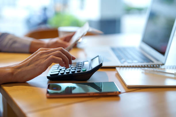 cropped shot of asian woman sitting at table doing financial plan and budget with calculator and laptop. - skatt bildbanksfoton och bilder