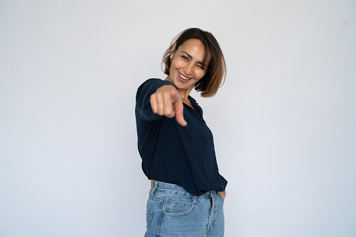 Excited woman pointing at camera. Female model in dark blue shirt recruiting new employees. Portrait, studio shot employment concept