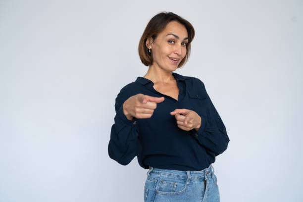 Playful woman pointing at camera with both hands stock photo