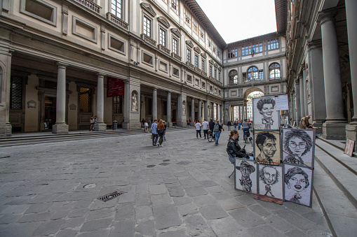 Street Artist at Florence in Tuscany, Italy, with people and drawings visible.