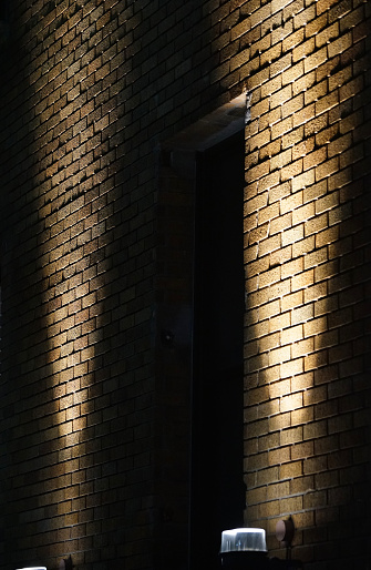 Two lights which light up the brick wall of the night