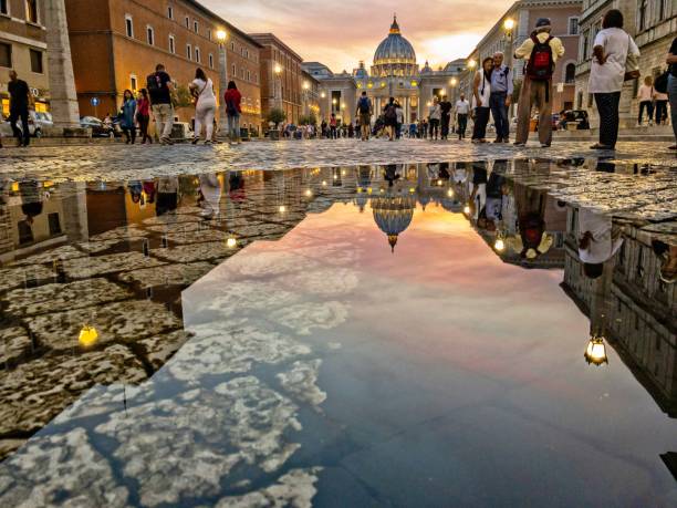 日没時に通りの水たまりにバチカンの建物が映る美しいショット - puddle rome reflection street ストックフォトと画像