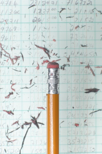 A vertical shot of a pencil in the background of eraser leftovers on the paper