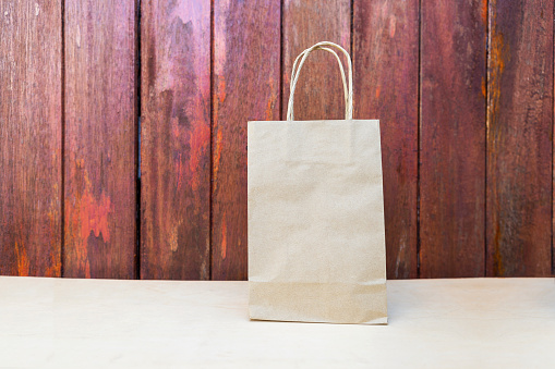 Paper bag on wood background, recycle brown paper bag with space on red wood background