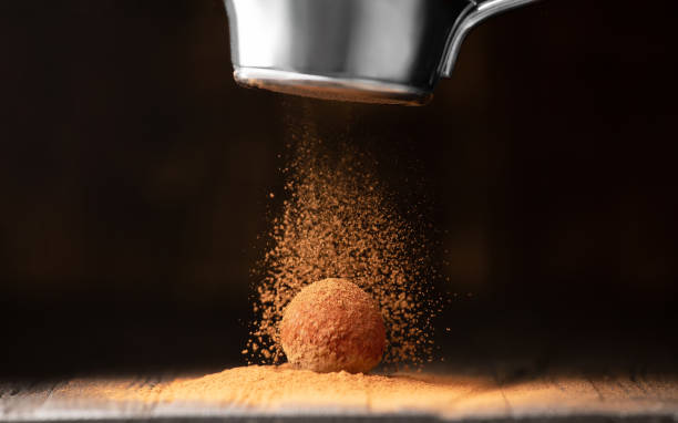 istock Delicious chocolate truffles sprinkled with cocoa on a black reflective background. 1452844540