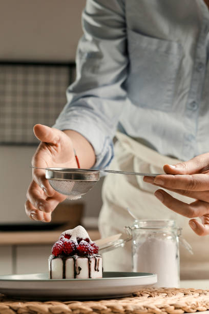 istock Housewife prepares a cupcake, sprinkles with sugar. 1452844612