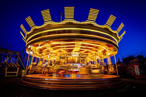 Newcastle upon Tyne, United Kingdom – June 26, 2019: A long exposure shot of a carousel spinning with colored lights at night, Hopping's fun in Newcastle upon Tyne