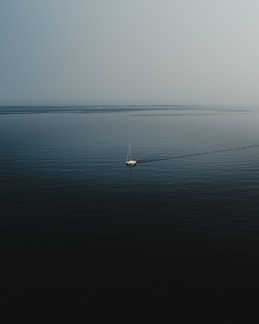 An aerial drone shot of a sailboat in the middle of the ocean