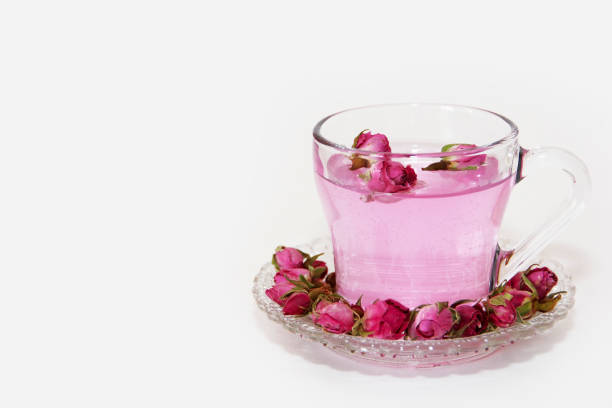 Pink tea with small pink rose buds in a transparent mug and in a decorative plate Pink tea with small pink rose buds in a transparent mug and in decorative plate pink tea stock pictures, royalty-free photos & images