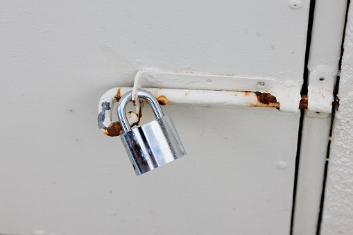 Silver padlock and latch on an old metal door