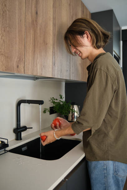 istock Asian young man rinsing fresh tomatoes in the sink. 1452856190