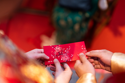 Cropped image of newlywed serving tea to elder on Chinese traditional tea ceremony and receiving red envelope