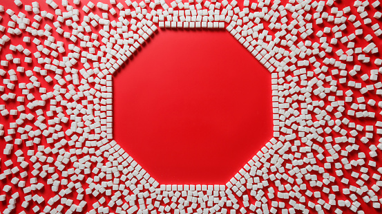 octagonal frame in the form of a stop sign made of sugar cubes with empty red background inside. stop eating refined sugar concept
