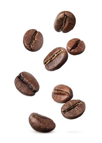 Muchos granos de café tostados volando sobre fondo blanco photo
