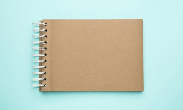 istock Notebook with brown paper pages on light blue background, top view 1452863787