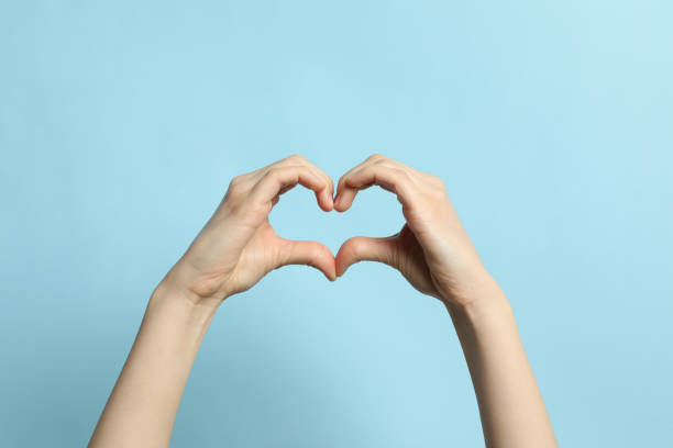 istock Woman making heart with her hands on light blue background, closeup 1452867140