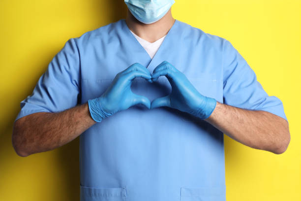 istock Doctor making heart with hands on yellow background, closeup 1452867143